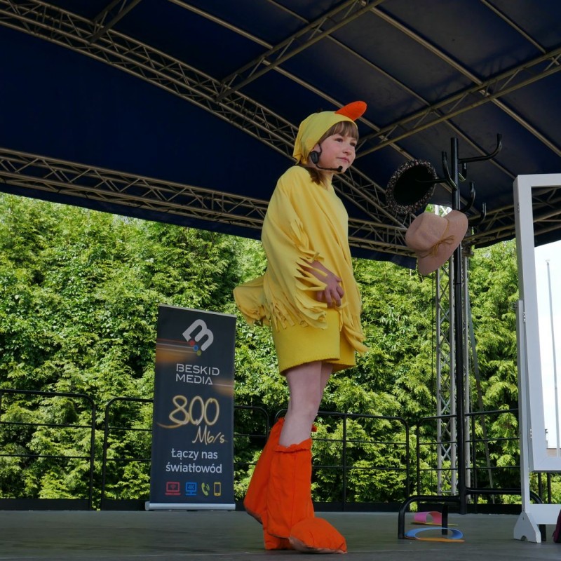 Dziewczynka przebrana za żółtego kurczaczki podczas występu na scenie plenerowej.