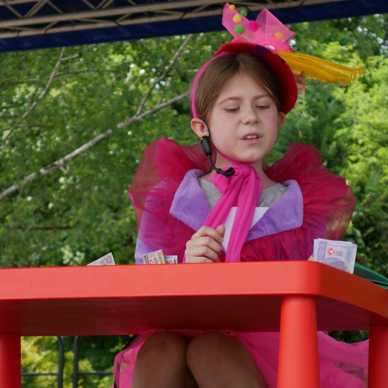 Dziewczynka w różowym kostiumie przy stoliku podczas występu ma scenie.