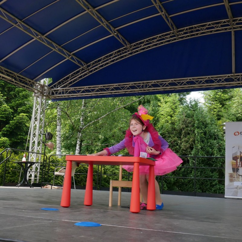 Dziewczynka ubrana w kolorowy strój podczas występu na scenie.