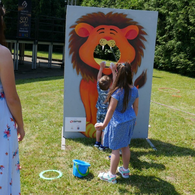 Dzieci przyglądają się planszy do zdjęć z dziurą i namalowanym lwem.