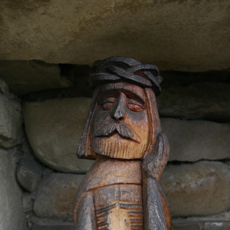 Drewniana figurka przedstawiająca mężczyznę z wąsem, podpierającego głowę ręką.
