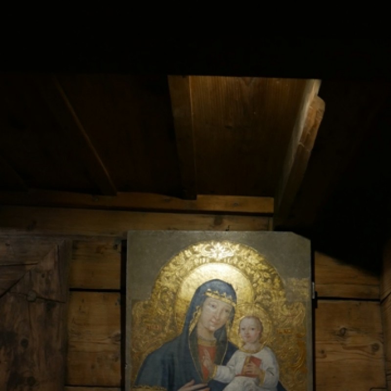 Obraz matki boskiej z Jezusem na drewnianej ścianie.