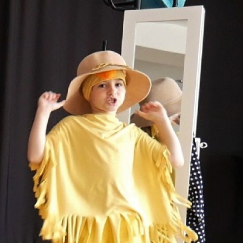 Dziewczynka w żółtym stroju i kapeluszu podczas recytacji.
