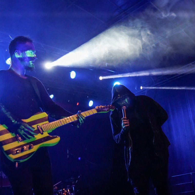 Dwóch mężczyzn – gitarzysta oraz wokalista, znajdują się na scenie, grając koncert. Otacza ich scena, oświetlona niebieskim światłem.