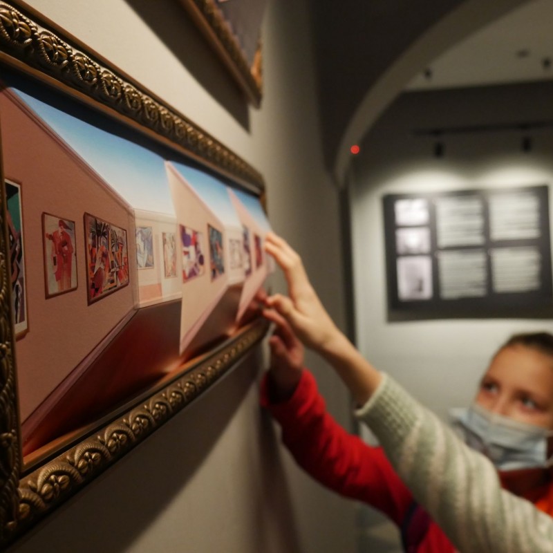 Dzieci eksplorują wystawę w muzeum dotykając eksponatu rękoma.