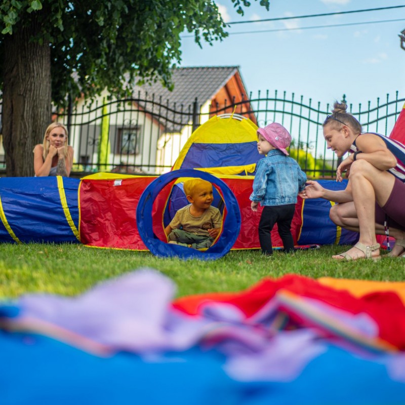 Fot. Łukasz Kuc/Kolorowe tory przeszkód z materiału, w nim bawiące się dzieci, oraz przypatrujące się im mamy.