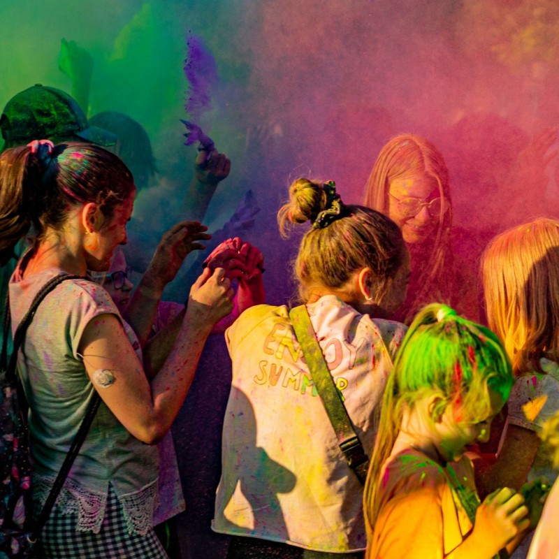 Fot. Łukasz Kuc/Festiwal kolorów, grupa ludzi w kłębach kolorowego dymu z proszkowanej farby.