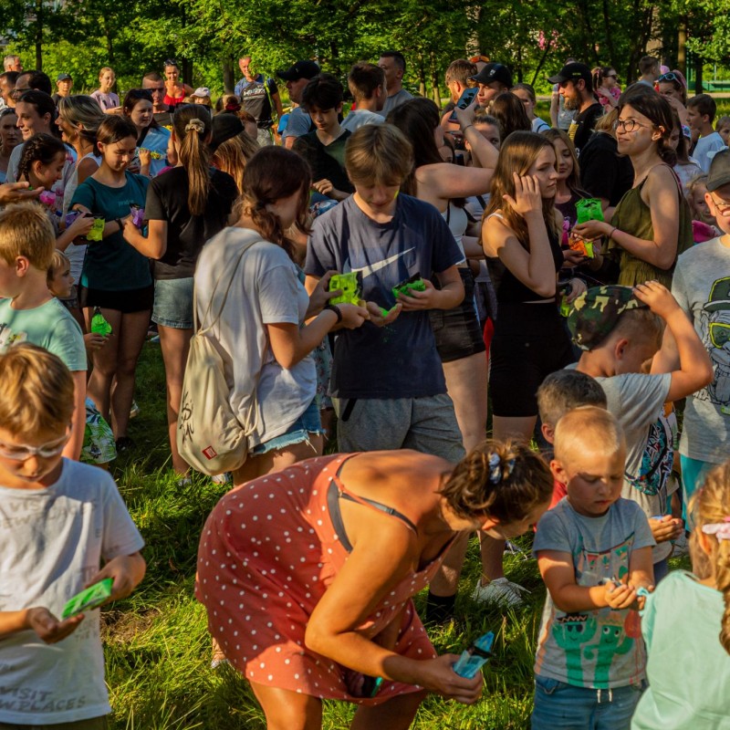 Fot. Łukasz Kuc/Grupa ludzi w parku przygotowująca się do wyrzutu kolorowego proszku na festiwalu kolorów.