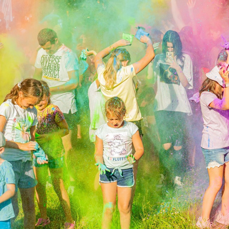 Fot. Łukasz Kuc/Festiwal kolorów, ludzie obsypujący się wzajemnie wielobarwnym proszkiem w kłębach kolorowego dymu.