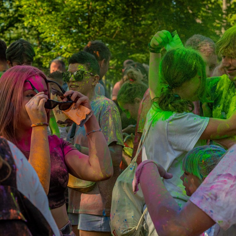 Fot. Łukasz Kuc/Grupa nastolatków i dzieci brudna od kolorowych farb w proszku obsypuje się nawzajem na festiwalu kolorów.