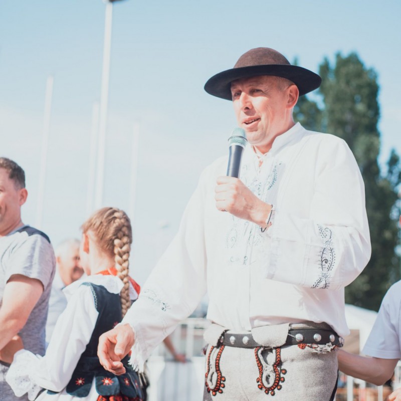 Fot. Łukasz Kuc/Mężczyzna ubrany w góralski strój mówi do mikrofonu, obok niego uczestniczący w zabawie ludzie.