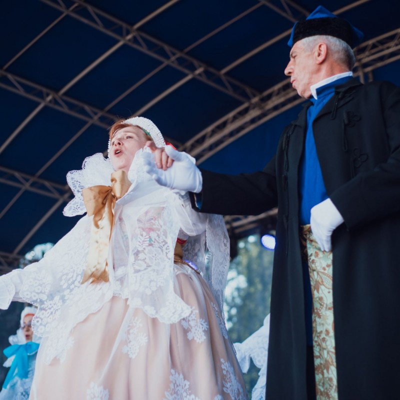 Fot. Łukasz Kuc/Grupa osób w kostiumach podczas śpiewu na na scenie plenerowej.