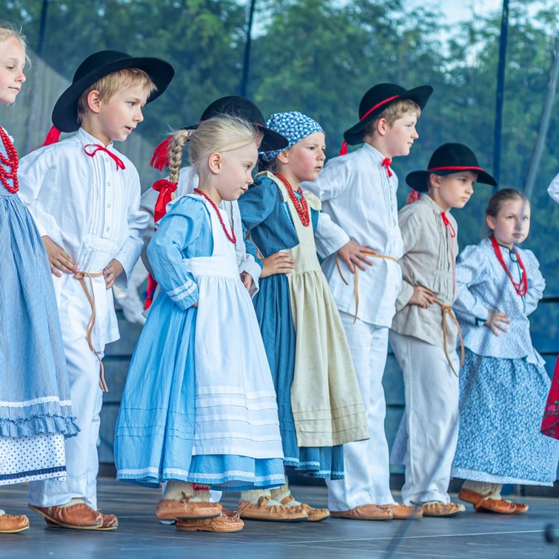 Fot. Łukasz Kuc/Grupa dzieci ubranych w regionalne stroje występuje na scenie plenerowej.