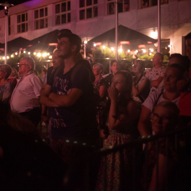 Fot. Łukasz Kuc/Ludzie oglądający widowisko wieczorem, w tle girlandy stworzone ze światełek.